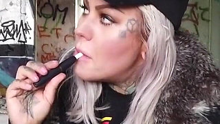 Blonde lady smokes an electronic cigarette on stair