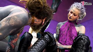 Inked submissive fellow double-pegged into submission by two relentless dominas